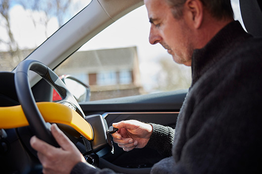 Image of a car owner locking their steering wheel to prevent car theft.