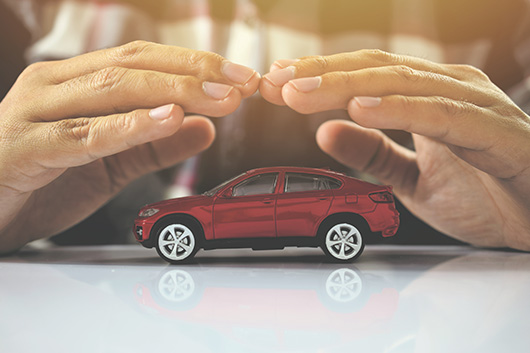 Image of hands covering a car, to symbolize protection and assurance.
