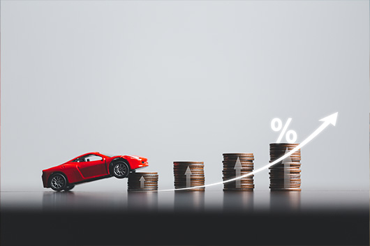 Image of a car driving over a stack of coins, to symbolize increasing interest rates